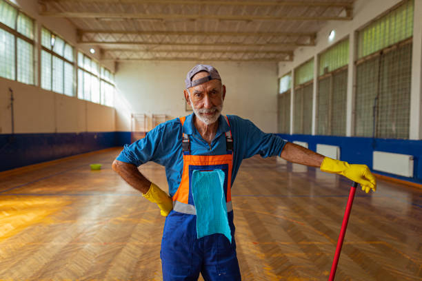 A male worker wearing work boots in a warehouse cleaning up a liquid spill on the floor.