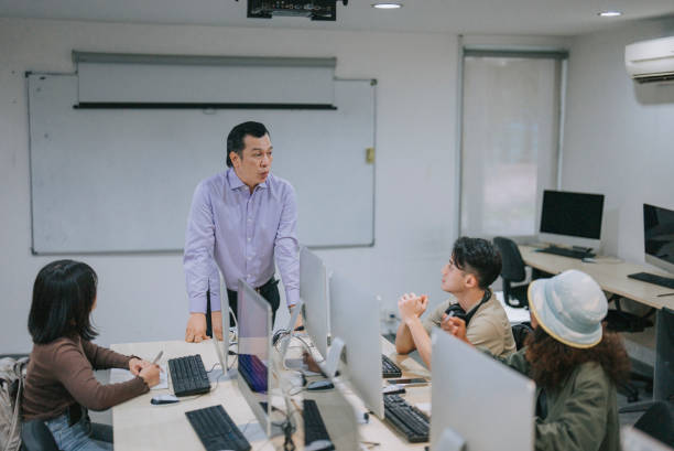istock Asian professor giving lecture to adult student in computer lab classroom 1418770826