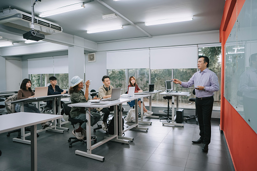 Asian malay college lecturer answering adult student question in classroom