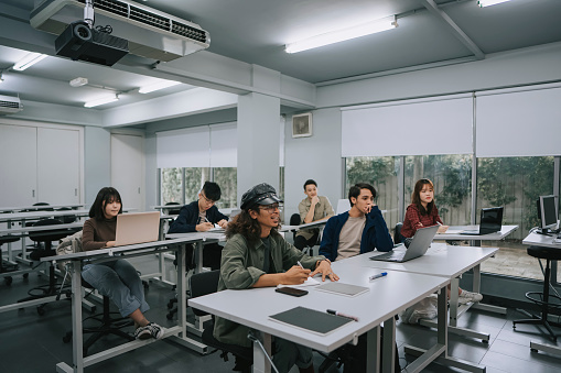 Diversify Asian college students concentrate listening to lecturer in classroom