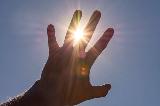 istock hand reaches for the sun. hand blocks the sun 1418773635