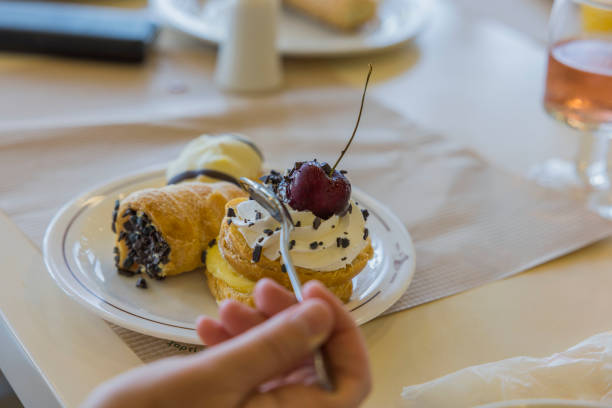 ケーキの上からチェリーを取るティースプーンを持つ女性の手のクローズアップビュー。 - unhealthy eating cherry chocolate close up ストックフォトと画像