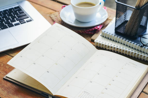istock Diary, Calendar, and agenda for Event Planner to plan timetable, appointment, organization, and management on office table. Desktop Calender and coffee placed on wooden desk. Calendar Background Concept 1418783667