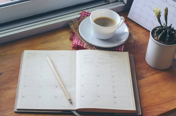 istock Diary, Calendar, and agenda for Event Planner to plan timetable, appointment, organization, and management on office table. Desktop Calender and coffee placed on wooden desk. Calendar Background Concept 1418783692