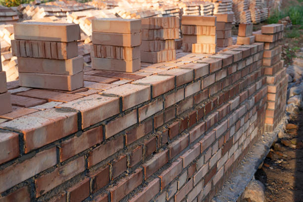 istock A perspective view of a brick wall under construction illuminated by the morning sun. There are stacks of bricks prepared for laying. Background. Texture. 1418785450