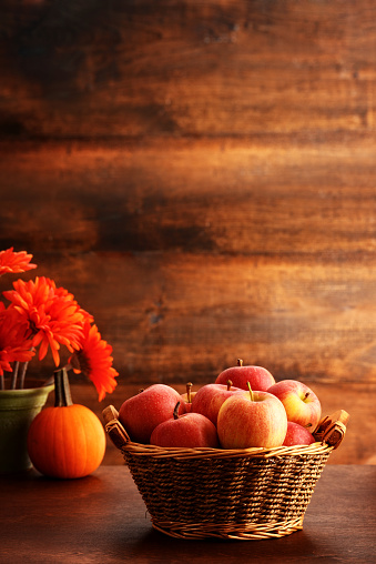 closeup wicker basket with gala apples and pumpkin on rustic wood