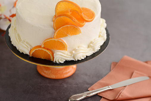 top view vanilla cake with orange slices and knife on a napkin