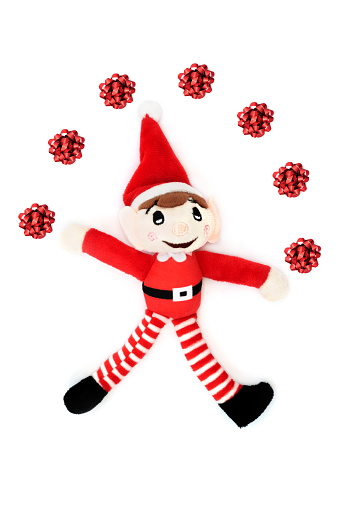 Christmas elf juggling red bow decorations retro santas helper festive toy on white background. Fun composition for the holiday season.