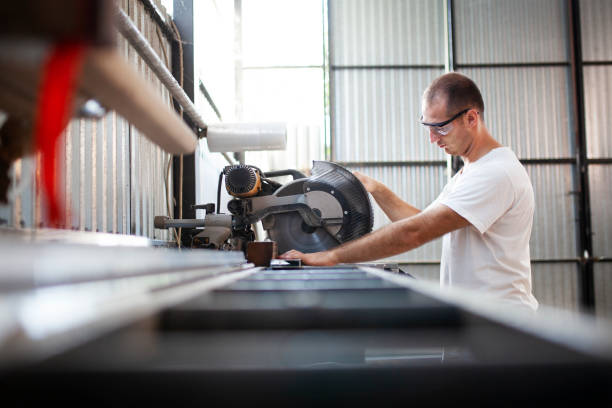istock Man on a workplace cutting aluminium bar with a circular saw, workshop interior 1418789397