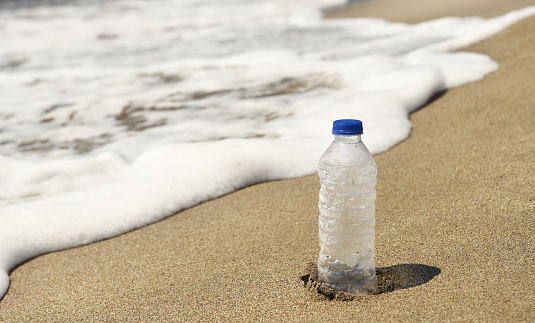 A used plastic bottle is lying on the beach. Environmental problems.