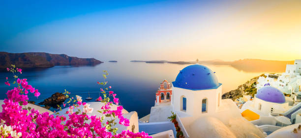 traditional greek village Oia of Santorini, with blue domes of churches in sunset light, Greece, wide panorama, toned