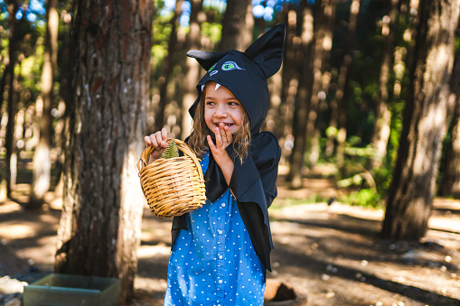 Little girl walking in the forest in bat costume on halloween