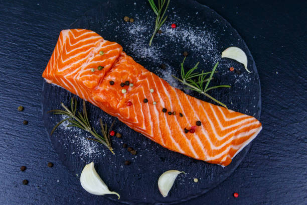 istock Raw salmon fillet with spices on black slate. Top view 1418800283