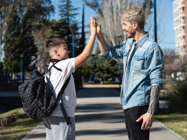 istock Father and son giving high five on the way to school on sunny day 1418802007