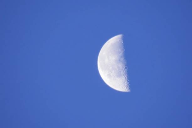 The brightness of the moon contrasts with the blue of the day.