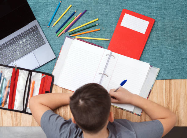 istock Top view of child studying at home with notebook and laptop. Blank copy space 1418803528