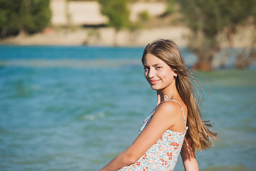Portrait of a beautiful happy teenage girl outdoors, on a lake shore.
