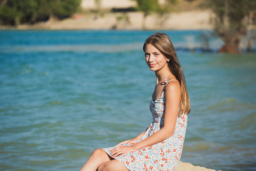 Portrait of a beautiful happy teenage girl outdoors, on a lake shore.