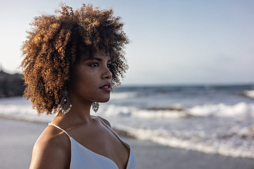 Portrait of beautiful young African woman in white dress with beach background.