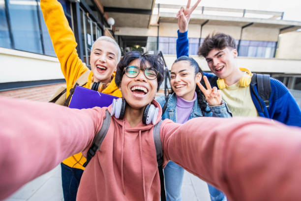 Group of multiracial students taking selfie picture at school - Happy young people hanging outside together - Teenagers in college campus - Back to school concept stock photo