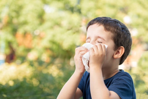 istock Allergic child sneezing covering nose with wipe in a par 1418809410