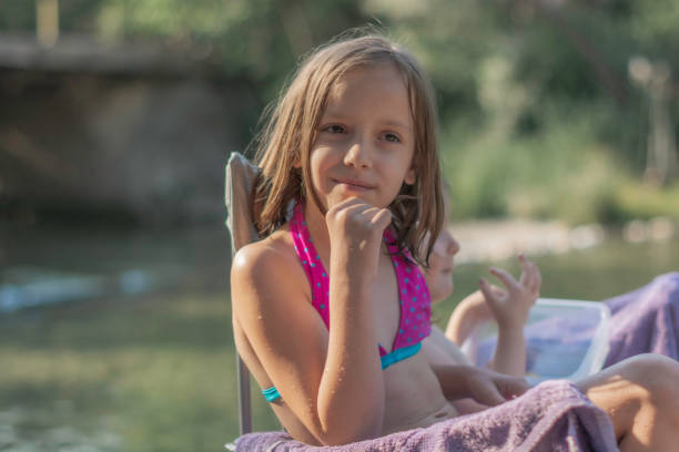 istock Girls sitting by the river during summer day 1418811033