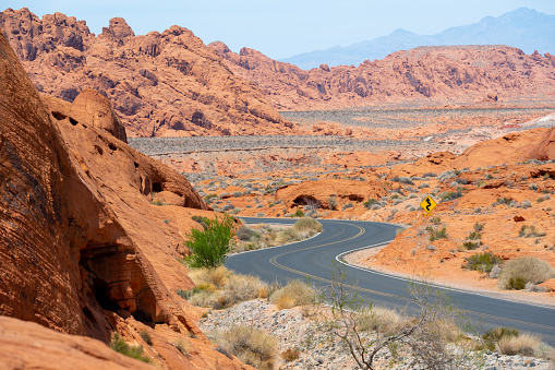 In Valley of Fire the road is winding and running through the red rock desert landscape. Seen in Nevada, USA, a hot day in the summer.
