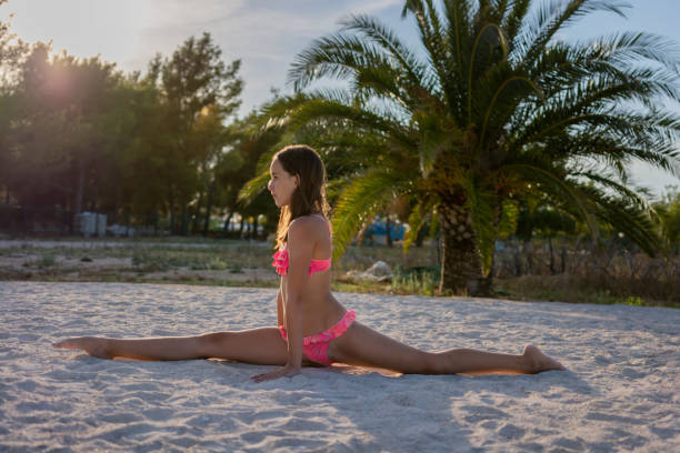 Young athletic girl during a rhythmic gymnastics exercises  on the beach