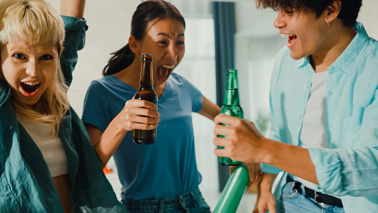 Close-up Group of happy Asian teenage people sit on couch watch cheer online sport soccer games world cup championship together. Woman shouting strike goal excited scream, facial expression concept.