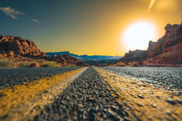 In Valley of Fire the road is running through the hot red rock desert landscape. Seen in Nevada, USA, a hot day at sunset from a cat perspective.