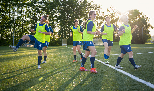 Female sports players exercising on field. Soccer team is stretching before match. They are in sports clothing. Sport and healthy lifestyle concept.