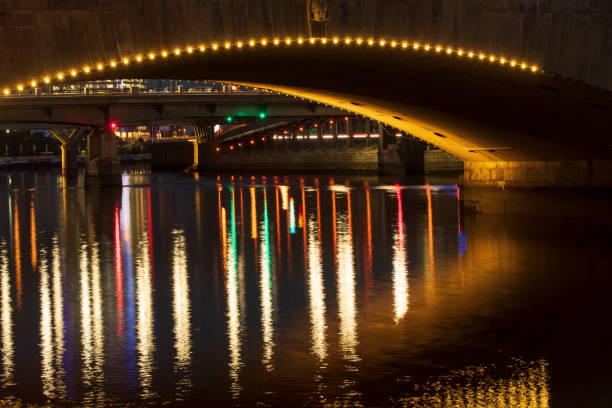 In the darkness of the night the city of Valladolid-Spain is illuminated, the artificial light of the street lamps is reflected in the waters of the Pisuerga River, under the bridge of a concrete arch.
