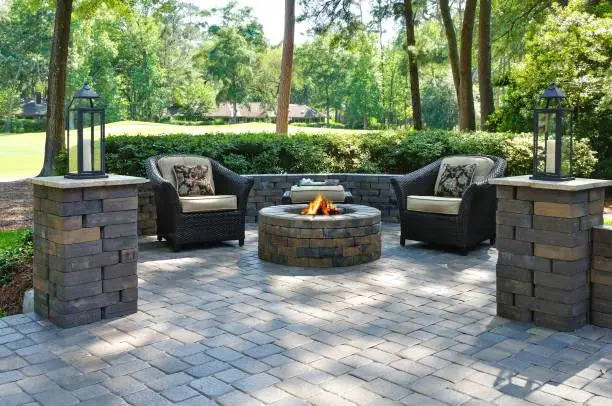 Photo of Beautiful outdoors pavers with two comfortable armchairs and a fire pit in a green environment