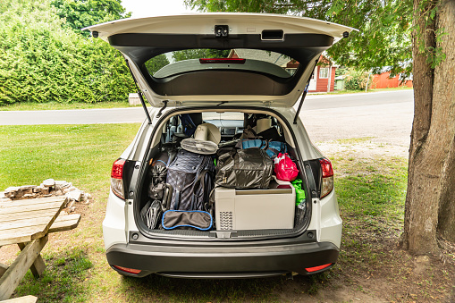Travel on car with camping luggage packed at the full car trunk, holiday concept. Outdoor activities items. Camping and exploring in summer season. Adventures and travel suv vehicle.