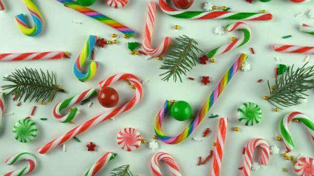 istock Christmas peppermint candy, red sprinkles and real fir or pine tree branches. Greenery with sugar sweets on white holiday table. 1418816721