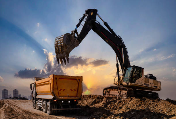 escavatore che carica dumper al tramonto - autocarro ribaltabile foto e immagini stock