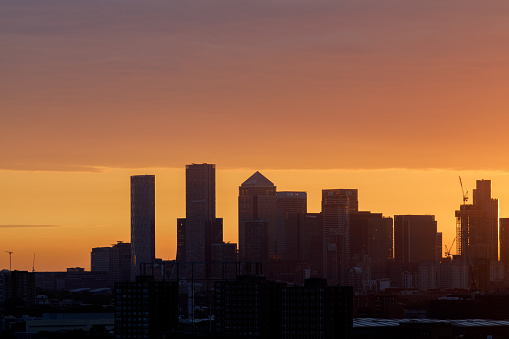 London, UK-29.7.22: silhouette of the Canary Wharf central business district in sunrise as seen from Southwark. Located on the Isle of Dogs It is one of the leading financial centres in the world