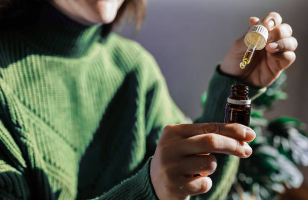 Woman holding a dropper of sublingual cbd cannabis hemp oil - Alternative medical treatment Woman holding a dropper of sublingual cbd cannabis hemp oil - Alternative medical treatment essential oil stock pictures, royalty-free photos & images