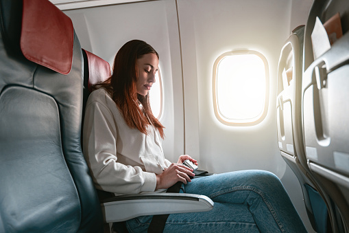 Woman passenger fastening seatbelt sitting in airplane before flight. High quality photo