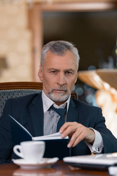 istock Businessman looking through his diary and drinking coffee while sitting in luxury hotel room 1418820620
