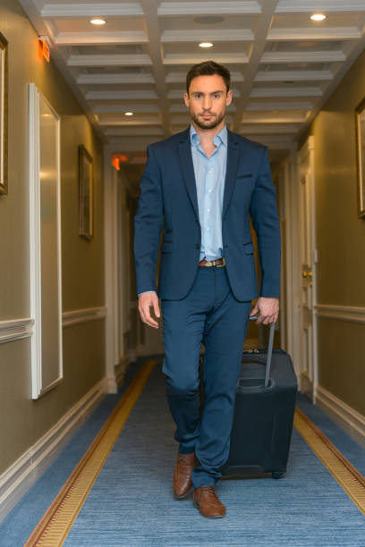 istock Happy young man with travel bag walking inside hotel 1418822180