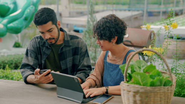 giovane coppia asiatica che si aiuta a vicenda a gestire le finanze per la propria attività. - farmer laptop selling internet foto e immagini stock