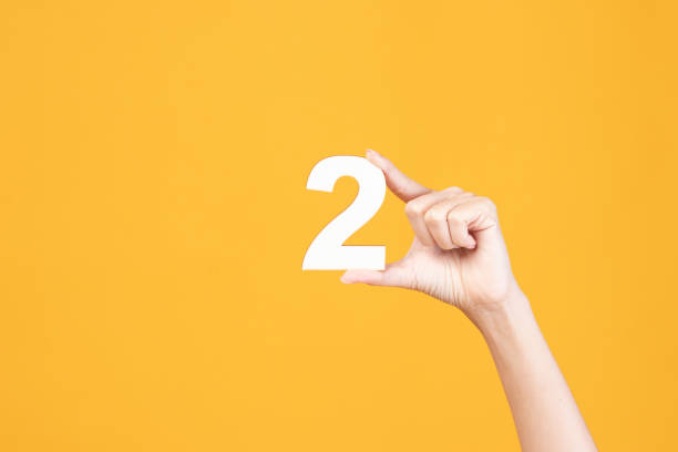 istock Hand holding wood number on yellow background. 1418827191