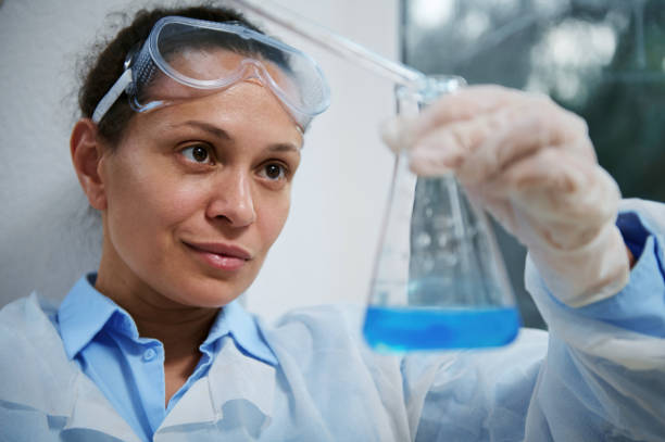 istock Pharmaceutical scientist in goggles, using a laboratory pipette, dropping reagent into a flat-bottomed flask with fluid 1418827276