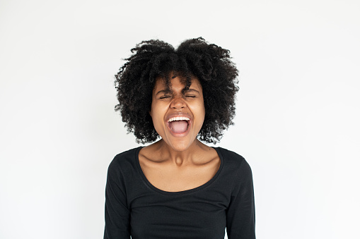 Portrait of upset African American woman standing and shouting. Young female model wearing black dress screaming with stress. Frustration concept