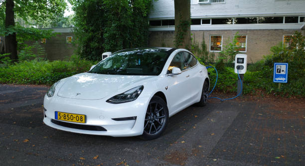 World's best sold electrical car gets filled up on a parking place Amersfoort, Netherlands - August 28 2022 A white Testa Model 3 being charged. This is a compact executive sedan that is battery powered. It's at the moment the world's top selling electric car tesla model 3 stock pictures, royalty-free photos & images