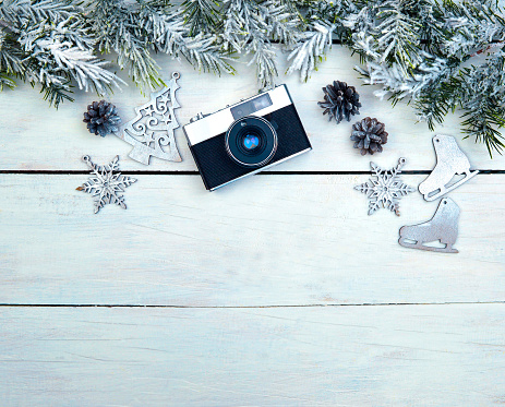 photography, technology and winter concept. Xmas greeting card. Christmas background with snow fir tree, camera and wooden toys . View from above with space for your greetings or photo.