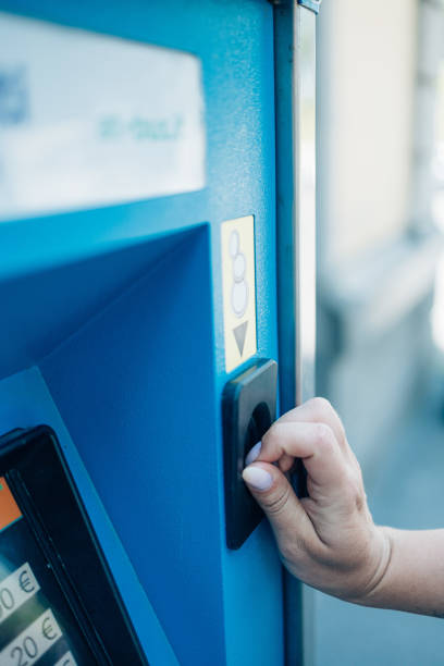 istock women’s hand with pink nails  inserting coin in to a ticket machine or parking meter 1418835872