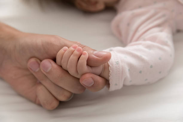 istock Tiny arm of cute newborn holds daddy thumb, close up 1418835997