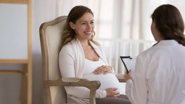 giovane paziente incinta risponde alle domande del ginecologo durante la visita - human pregnancy midwife healthcare and medicine visit foto e immagini stock